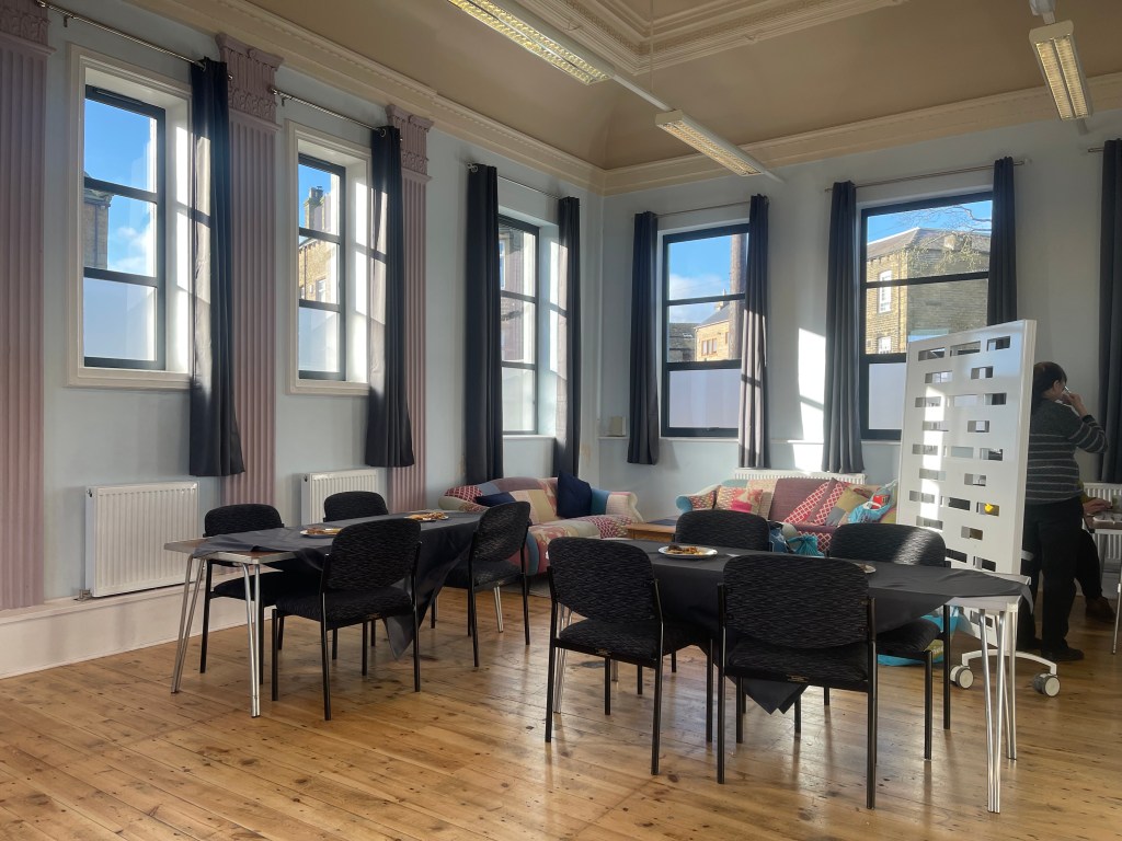 Hall set up for coffee morning, blue skies shine through window
